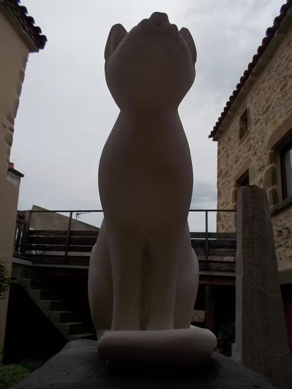 Chat Bastet en calcaire coquillé sur son coussin de basalte, élancé.